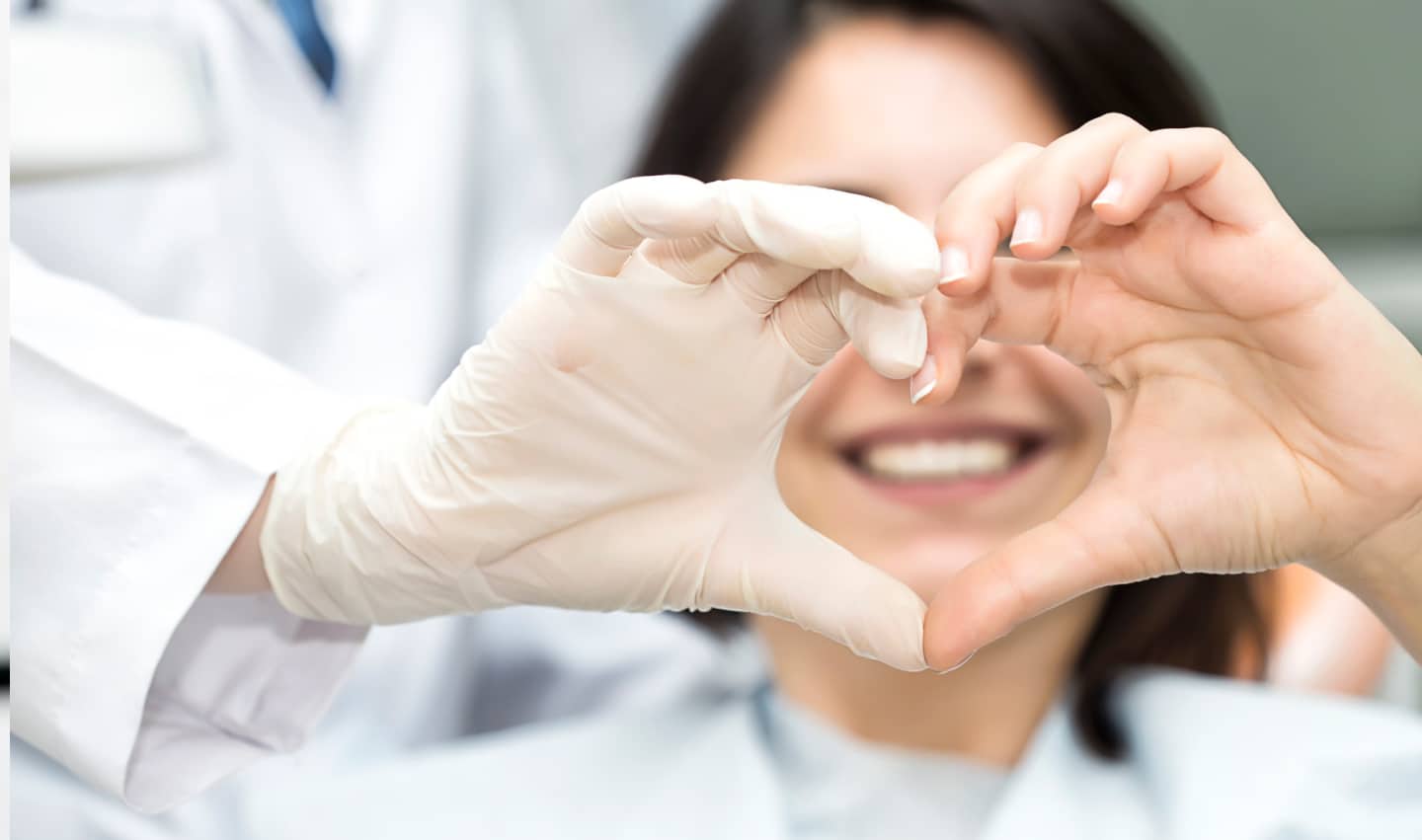 Patient making the heart shape with her hands with her doctor.